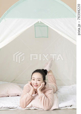 Asian woman in pajams under indoor bed tent 76398220