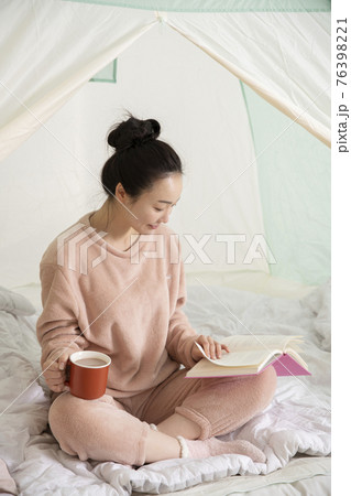 Asian woman in pajams under indoor bed tent 76398221