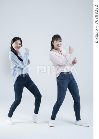 two Asian women, sisters dancing same move, white background 76398222