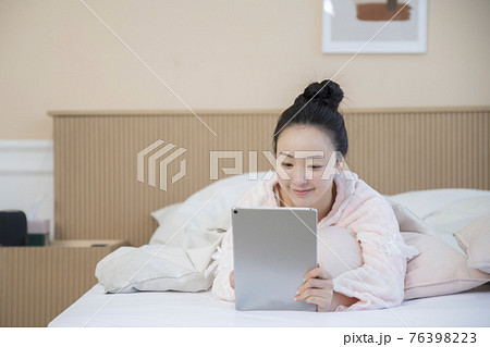 Asian woman using digital tablet in bed 76398223