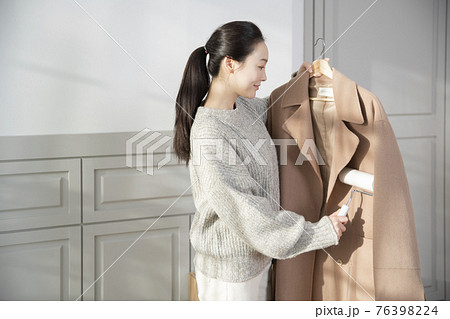 Asian woman using roller tape on winter coat 76398224