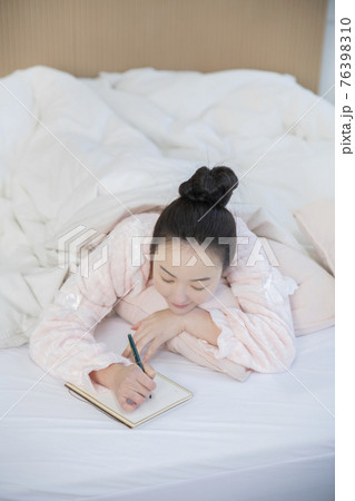 Asian woman writing planner, diary in bed 76398310
