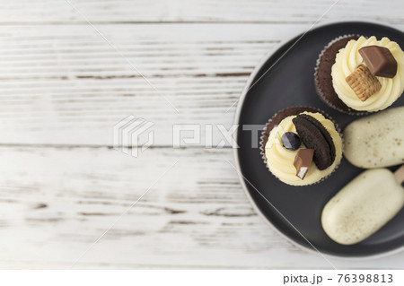Muffins and cupcakes on tray. Cookie ice creams on a stick. Wooden background 76398813