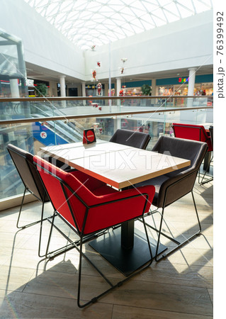 A table and soft chairs for visitors to the food court of a modern shopping center. A table and soft chairs for visitors to the food court of a modern shopping center. 76399492