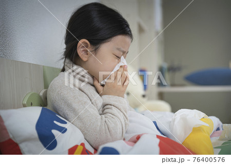 Asian little girl blowing nose on the bed 76400576