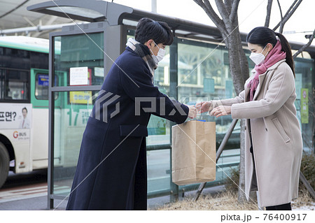 Asian woman and man with face masks handing over paper bag, face to face selling second hand stuffs concept Asian woman and man with face masks handing over paper bag, face to face selling second hand stuffs concept 76400917