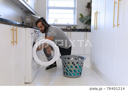 Caucasian man wearing gray tshirt and doing laundry Caucasian man wearing gray tshirt and doing laundry 76401214