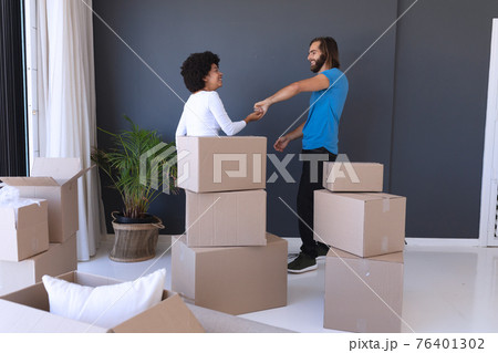 Happy diverse couple moving house smiling and dancing Happy diverse couple moving house smiling and dancing 76401302