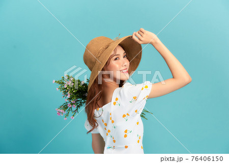 Girl in hat and flower dress poses with bouquet. Girl in hat and flower dress poses with bouquet. 76406150