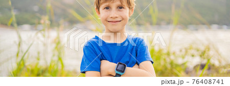Boy uses kids smart watch outdoor against the background of the garden BANNER, LONG FORMAT Boy uses kids smart watch outdoor against the background of the garden BANNER, LONG FORMAT 76408741
