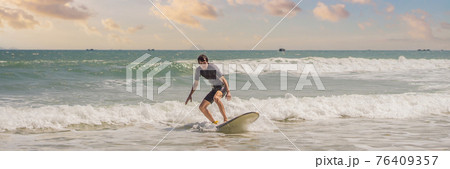 Young surfer learning to surf in black wetsuit, sunny day on ocean beach BANNER, LONG FORMAT Young surfer learning to surf in black wetsuit, sunny day on ocean beach BANNER, LONG FORMAT 76409357