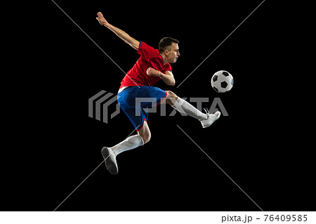 Young Caucasian soccer football player practicing isolated on black background. 76409585