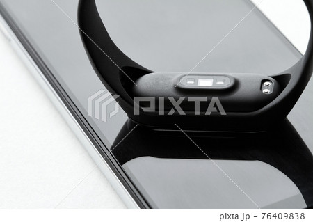 Black fitness watch or activity tracker. Fitness tracker lies on the smartphones. Closeup, selective focus 76409838