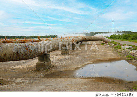 View of the rusty industrial water cooling installations against the background of the power plant. 76411398