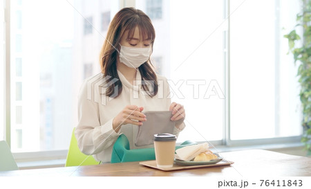 カフェで朝食を取るマスク女性_コロナ禍 76411843
