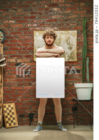 Portrait of young man with blank sign like social media screen sitting at home. 76412032