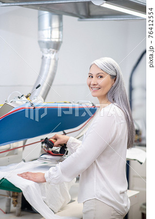 Woman with iron near counter at dry cleaning 76412554