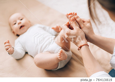 Caring mother gives foot and leg massage to her newborn baby. Caring for the health of children Caring mother gives foot and leg massage to her newborn baby. Caring for the health of children 76413819