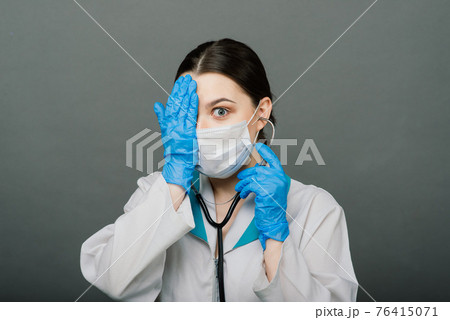 Beautiful female doctor in mask looking away and thinking about something. 76415071