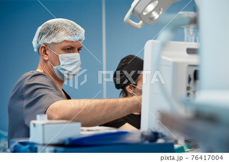Anesthesiologist keeping track of vital functions of the body during cardiac surgery. Surgeon looking at medical monitor during surgery. Doctor checking monitor for patient health status. 76417004