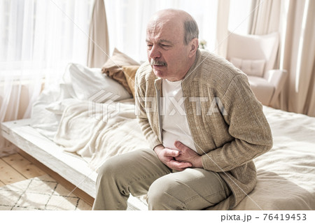 Elderly man with bellyache holding stomach with his hand Elderly man with bellyache holding stomach with his hand 76419453