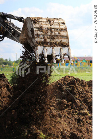 an excavator digs a ditch in a vacant lot. Laying the pipeline to the new house. reportage shooting. an excavator digs a ditch in a vacant lot. Laying the pipeline to the new house. reportage shooting. 76420680