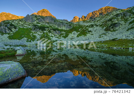 Mountain landscape and glacial Taul Portii lake in Retezat National Park, Carpathian Mountains, Romania, at sunrise Mountain landscape and glacial Taul Portii lake in Retezat National Park, Carpathian Mountains, Romania, at sunrise 76421342