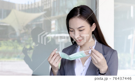 Young Asian woman has a mask ready to wear. Prevention of pathogens or epidemics of the CORONA VIRUS, Initial protection. Helping to reduce the spread of germs, Face mask, Safety first Young Asian woman has a mask ready to wear. Prevention of pathogens or epidemics of the CORONA VIRUS, Initial protection. Helping to reduce the spread of germs, Face mask, Safety first 76437446