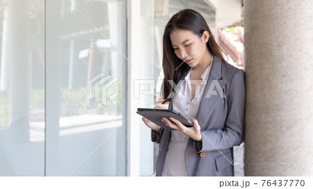 Young Asian business women communicate with business partners through tablets, Talking with wireless technology, Business data analysis using a tablet, Digital document. 76437770