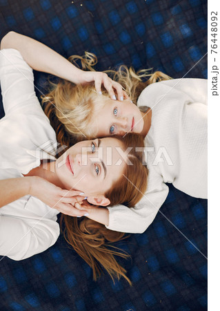 Mother with little daughter lying on a plaid in a summer park Mother with little daughter lying on a plaid in a summer park 76448092