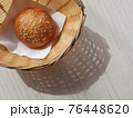 Sunny Breadbasket with long shadow on white wooden table top view. Closeup Bun in basket modern banner snack food decorative design with copy space. Bright Corner bakery flat lay horizontal concept 76448620