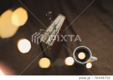 A book with flowers and cup of coffee on dark background top view A book with flowers and cup of coffee on dark background top view 76448750