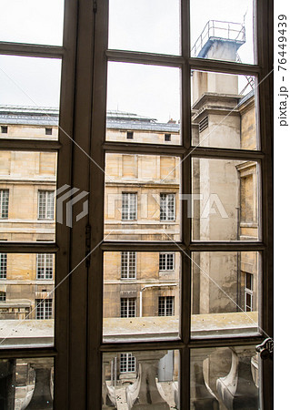 フランスパリのベルサイユ宮殿の中　格子窓越しに見える薄茶色の石造りの建物 76449439