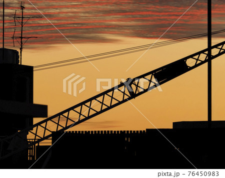 クレーンのシルエットと夕焼け空 クレーンのシルエットと夕焼け空 76450983