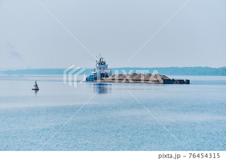 pusher tug pushes dry bulk cargo barge with sand on the river in the morning haze pusher tug pushes dry bulk cargo barge with sand on the river in the morning haze 76454315