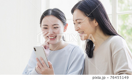 一緒にスマホを見る二人の女性 76455149