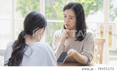一緒にスマホを見る二人の女性 一緒にスマホを見る二人の女性 76455173