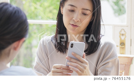 一緒にスマホを見る二人の女性 76455176