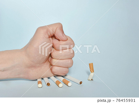 Hand destroying cigarettes on blue background. Quit smoking, World No Tobacco Day on May 31 concept. Selective focus 76455931
