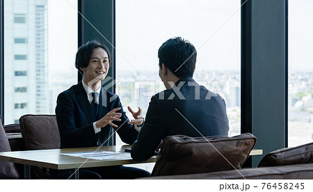 オフィスで会話するビジネスマン 76458245