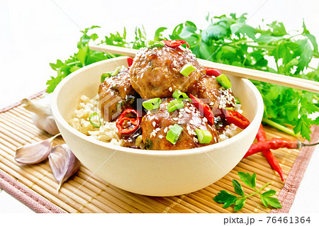 Meatballs in sweet and sour sauce with rice on light wooden board 76461364
