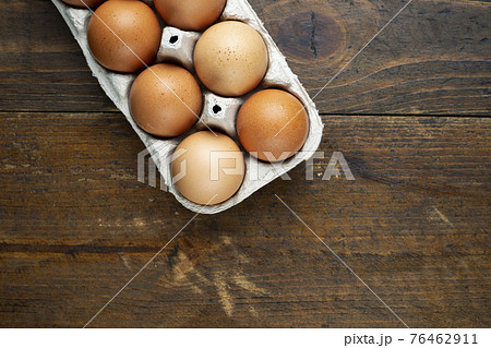 Chicken eggs in a tray on a wooden table. 76462911