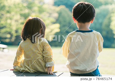 ベンチに座る兄妹の後ろ姿の写真素材