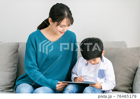 ソファーに座ってタブレットを見る親子 76465179