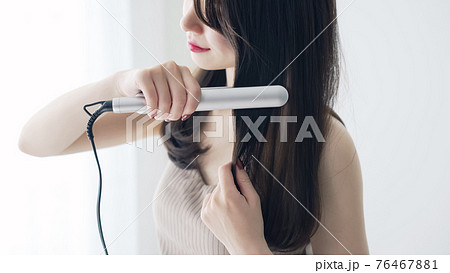 ヘアアイロンを使う女性　スタイリング 76467881