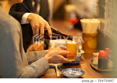 居酒屋でグラスにビールを注ぐ手元の写真素材