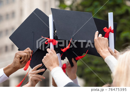 Graduation hats and diplomas in students hands, closeup Graduation hats and diplomas in students hands, closeup 76475395