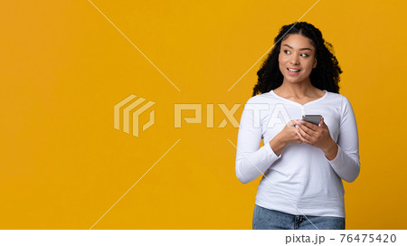 Black Woman With Smartphone In Hands Looking At Copy Space With Interest Black Woman With Smartphone In Hands Looking At Copy Space With Interest 76475420