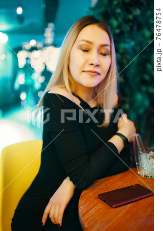 Beautiful girl in black dress in restaurant. Beautiful girl in black dress in restaurant. 76478754
