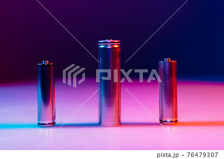 AA and 8650 Li-ion silver batteries on illuminated by multicolored light AA and 8650 Li-ion silver batteries on illuminated by multicolored light 76479307